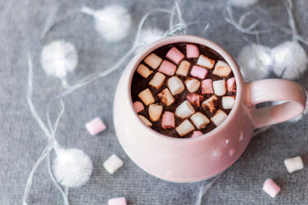 hot chocolate  pink ceramic mug marshmallows and garland  gray knitted backgroundの写真素材