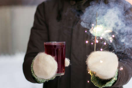 hands in mittens with mulled wine   and sparkler , outdoor celebrationの写真素材