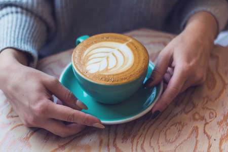 woman with a Cup of cappuccino in a cafe, closeup hands with a cupの写真素材