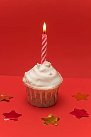 cute cupcake  with burned candle and confetti red  backgroundの写真素材