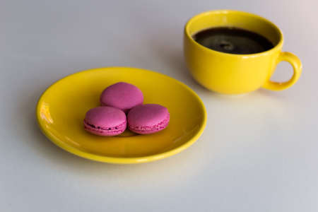 three macarons on a plate and cup of a black coffeeの写真素材