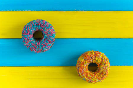 top view colorful donuts blue yellow backgroundの写真素材