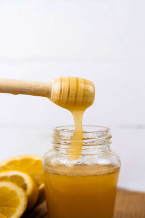 jar of honey and lemon slices on a wooden board light backgroundの写真素材