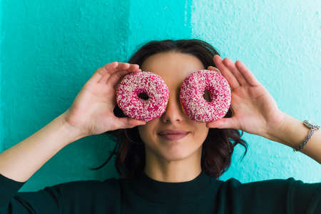cute woman holding donuts near her eyesの写真素材
