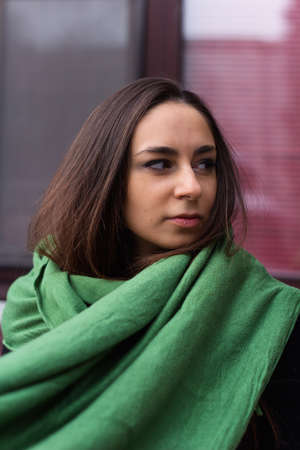 beautiful young brunette woman in green scarf street portraitの写真素材