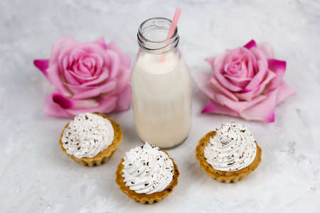 top view milk bottle, roses, sweet cupcakes concrete light backgroundの写真素材