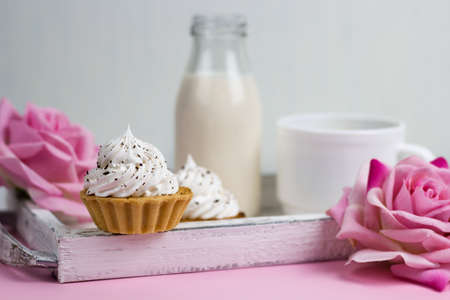 cupcake on a wooden tray with rose flowers, milk bottle and coffee cup, romantic breakfast on a vintage wooden trayの写真素材