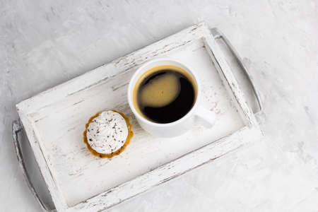 top view cupcake with cream decorated with chocolate chips  and coffee cup on a vintage wooden tray concrete backgroundの写真素材