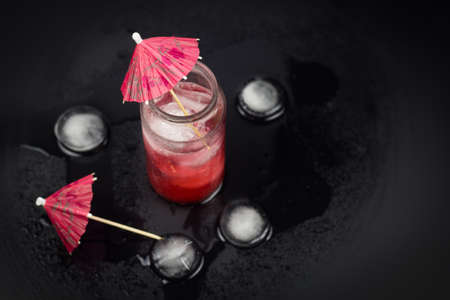 top view glass jar with red cocktail and ice,decorated with umbrellaの写真素材