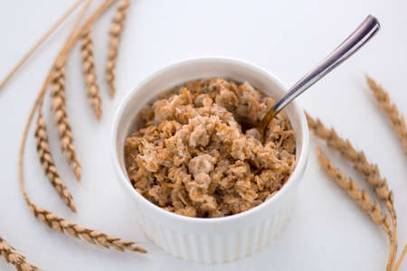 oatmeal bowl on the table and ears of oatsの写真素材