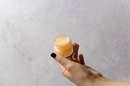 female hands holding cosmetic product in a glass jarの写真素材