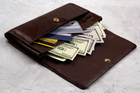 opened brown leather wallet full of dollars and credit cards