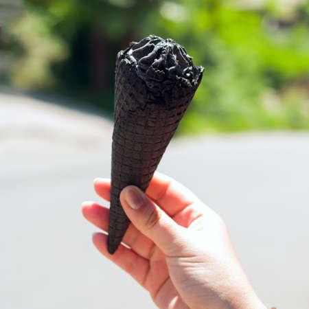 black ice cream with charcoal in a woman's hand