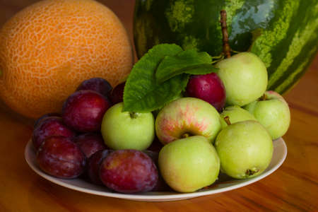 fresh sweet fruits on a plate on a wooden tableの写真素材