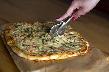 fresh hot homemade pizza on a wooden table women's hand close upの写真素材