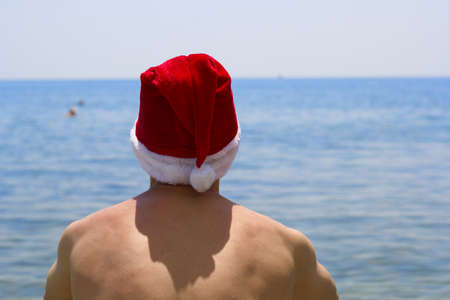 man with his back to the camera in a Santa Claus hat on the sea shore tropical Christmasの写真素材