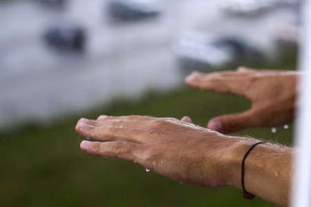 man's hands under rainの写真素材