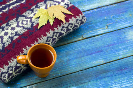top view warming drink autumn leaves on a knited sweater bue wooden boards for backgroundの写真素材