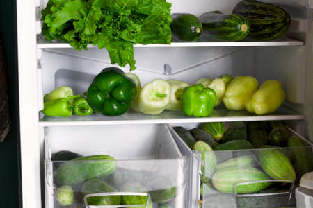 open fridge shelves and drawers full of green vegetables, raw food, veganism, healthy food, healthy lifestyle, food storage conceptの写真素材