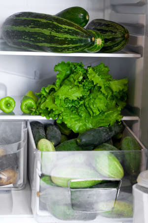 open fridge shelves and drawers full of green vegetables, raw food, veganism, healthy food, healthy lifestyle, food storage conceptの写真素材