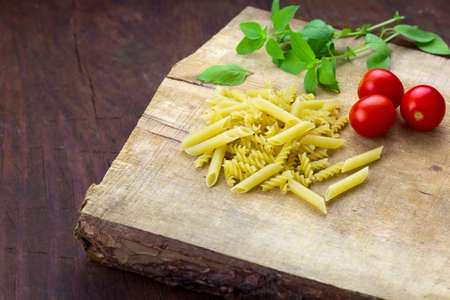 pasta,tomatoes,basil on a wooden cutting boardの写真素材