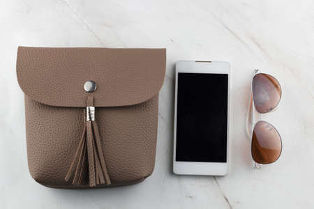 top view women  bag  phone  and sunglasses on  marble table