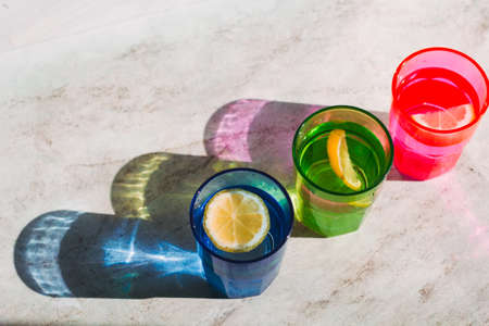 top view bright glass with drink and lemon slice, beautiful shadow on a stone marble table  ,detox, creativity,fashion conceptの写真素材