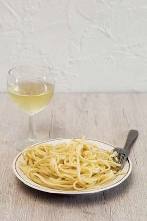 pasta and white wine glass on a wooden tableの写真素材