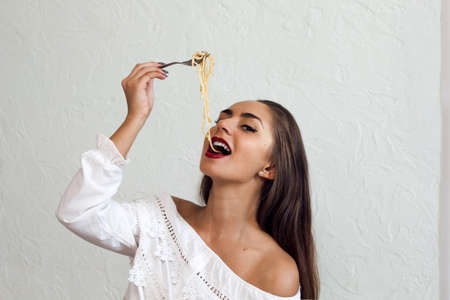 beautiful young woman eating pasta portraitの写真素材