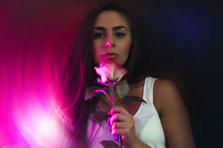 portrait of young beautiful woman with tanned skin in pink neon background, blurred background. club, bar, night lifeの写真素材