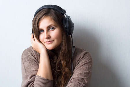 young beautiful  caucasian woman with curly hair in sweater with headphones listen and enjoy...