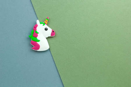 little unicorn toy head on a blue and green paper background copy spaceの写真素材