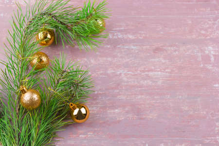 green fir branches with golden christmas  balls frame top view shabby brown background copy space