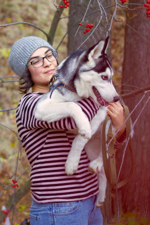 Beautiful young woman  with husky dog sitting on her hands in the parkの写真素材