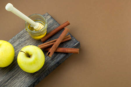top view honey jar,apples  and cinnamon on a wooden board brown background copy spaceの写真素材