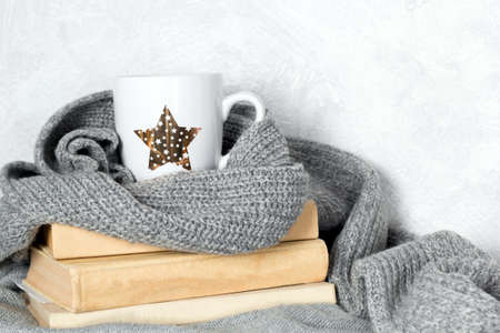 cute white cup with drink and gray knitted sweaters and scarf, cozy autumn  or winter weekends conceptの写真素材