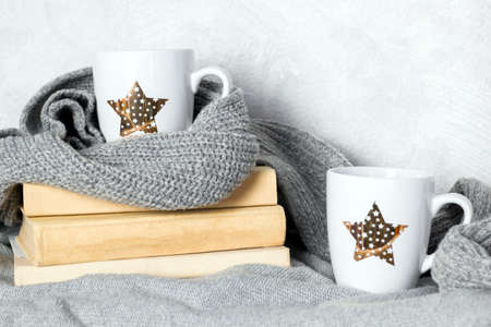 cute white cup with drink and gray knitted sweaters and scarf, cozy autumn  or winter weekends conceptの写真素材