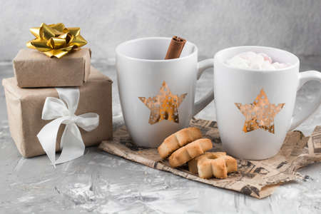 winter hot sweet drink cups with gift boxes and cookies on a shabby gray concrete backgroundの写真素材