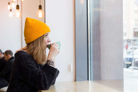 woman sitting in a cafe with a mug of hot drink