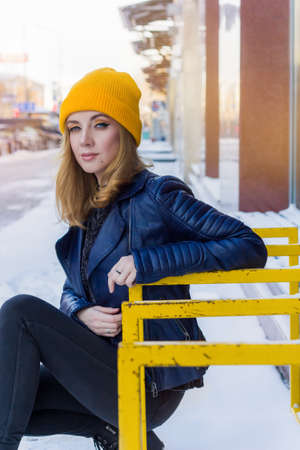 beautiful woman in yellow knitted hat and blue leather jacket street portraitの写真素材
