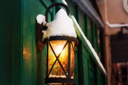 retro lantern covered with snow with shining light and bokehの写真素材