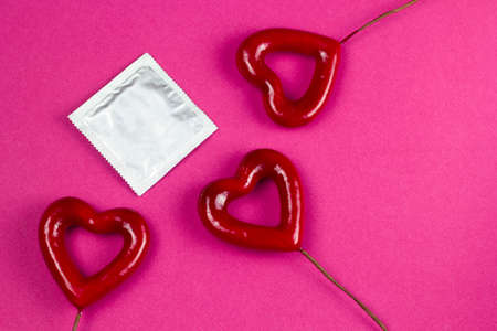 top view condom and 3 red hearts pink backgroundの写真素材