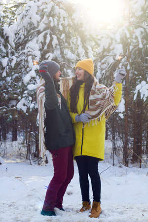 selective focus sparkler in hands of young beautiful man and woman kissing  and celebrate winter...