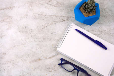 top view succulent in concrete pot , white sheet of paper, pencil and glasses on a marble backgroundの写真素材