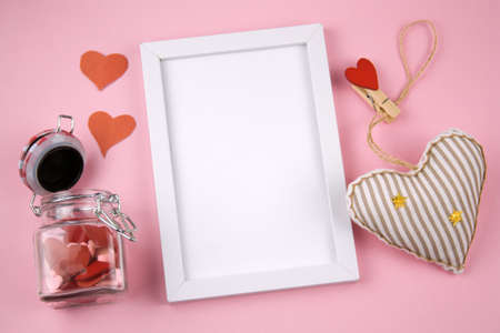 top view empty white frame copy space , stuffed toy in a shape of heart and jar with red hearts on a pastel pink backgroundの写真素材