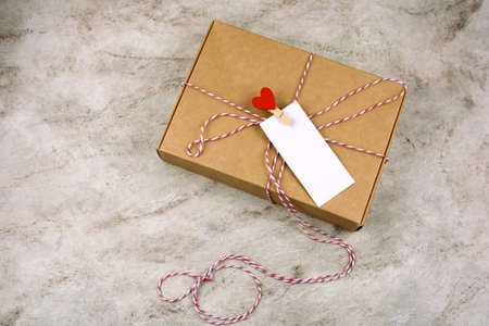 op view cardboard box with cloth pin with red heart and empty white label with place for text marble backgroundの写真素材