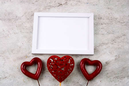 top view white mock up wooden frame and three red hearts on a marble background