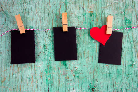 three blank mock up labels and paper red heart on cloth pins hanging on a rope on a vintage rough...