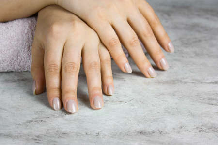 close up of beautiful female hands with manicure on marble table,  healthy hands skin and nails conceptの写真素材