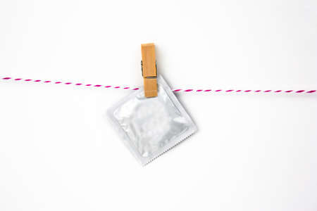 condom pack on clothes pin on a white backgroundの写真素材